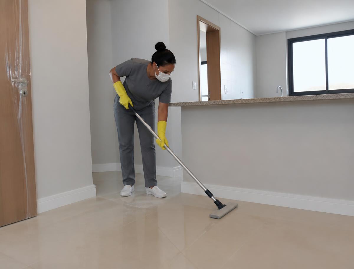 Profissional de limpeza higienizando o piso de um apartamento recém-reformado, em imagem ilustrativa